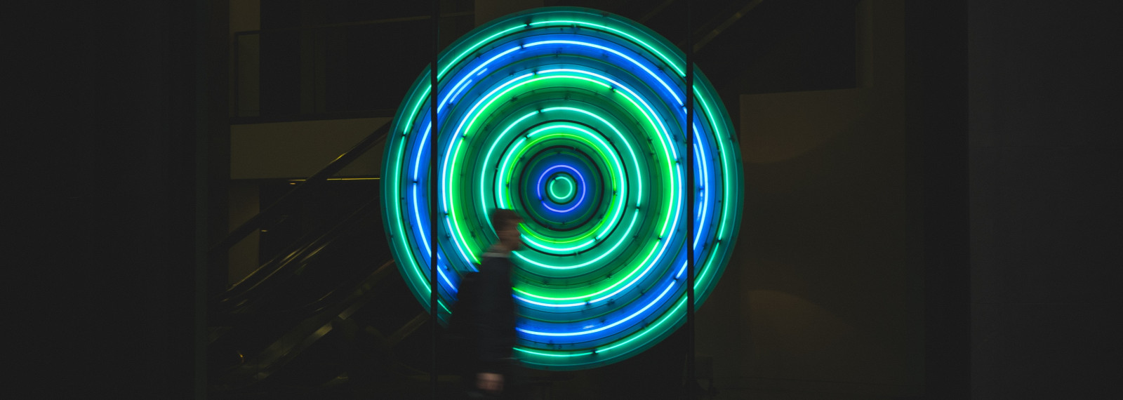 Image of circular LED lights in a shop window with a person walking in front of it