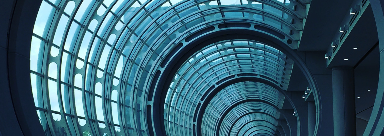 Looking down a circular glass tunnel towards a corporate looking building
