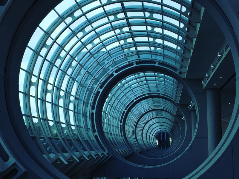 Looking down a circular glass tunnel towards a corporate looking building