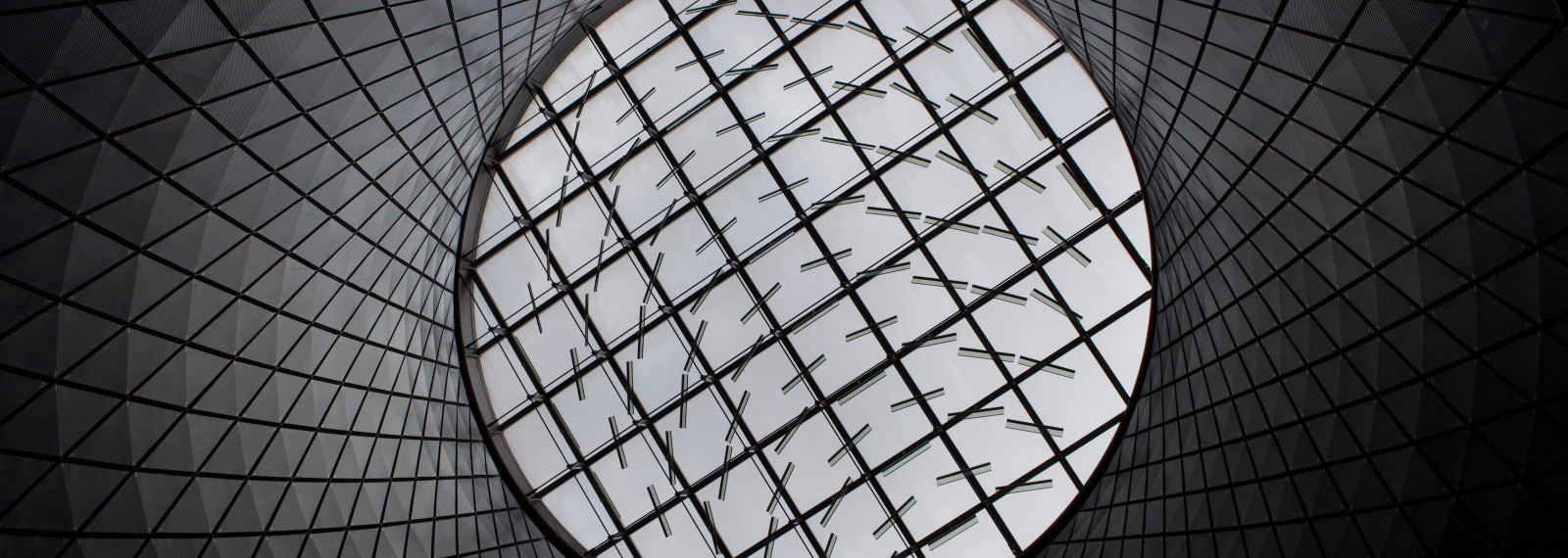 Looking up at a patterned glass ceiling through a circular tunnel