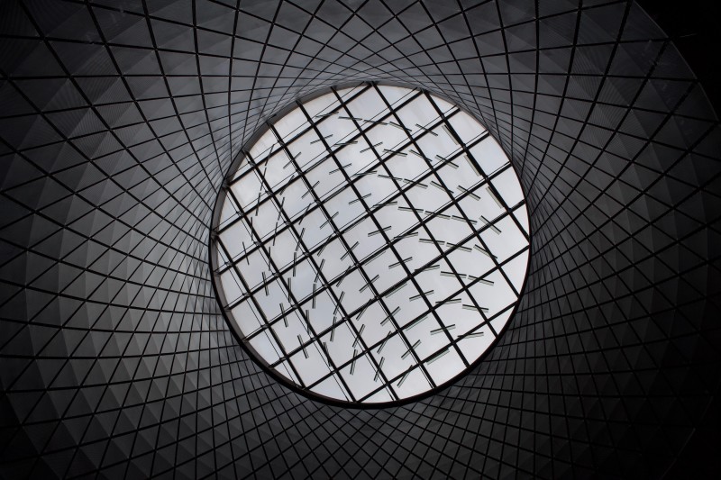 Looking up at a patterned glass ceiling through a circular tunnel