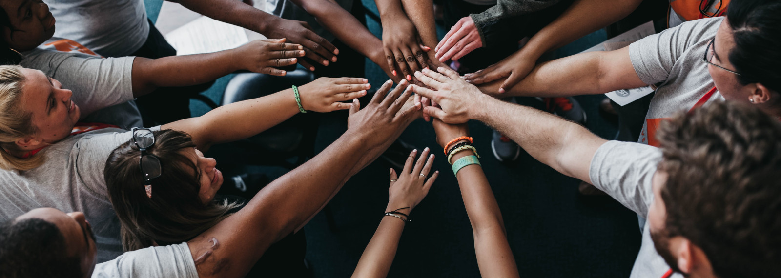 Image of a circle of people touching hands in a huddle