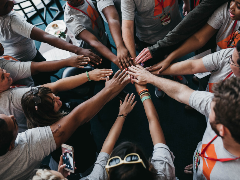 Image of a circle of people touching hands in a huddle