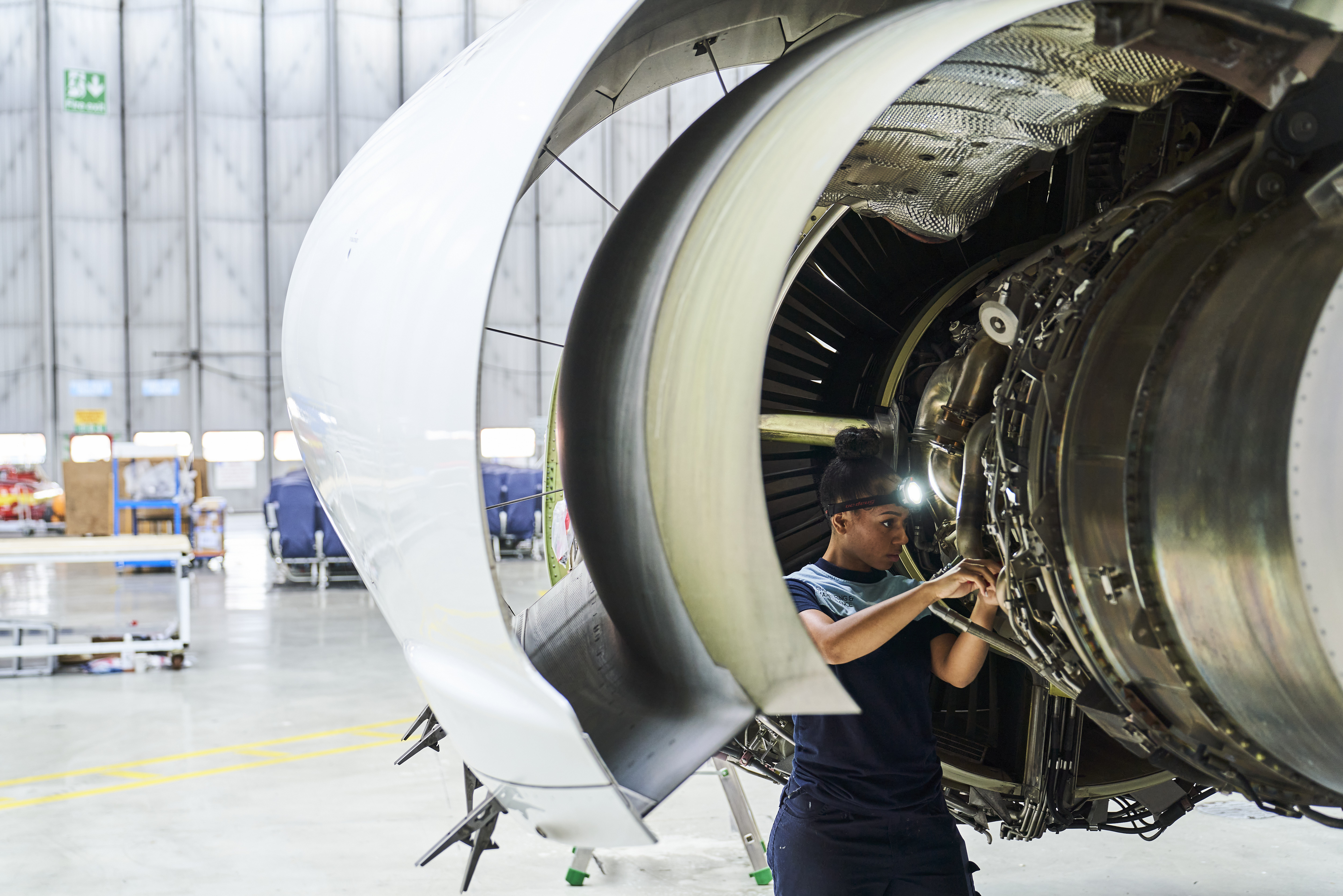 TUI Aircraft Engineer working on a commercial jet turbine inside of an aircraft hanger at Luton airport. She is undergoing servicing and general maintenance tasks.