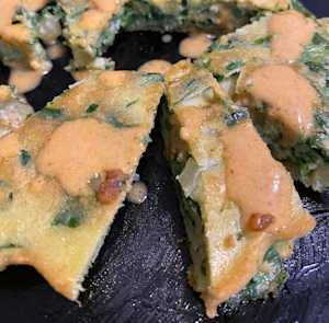 package with swiss chard and green onion in the batter, topped with spicy sesame sauce