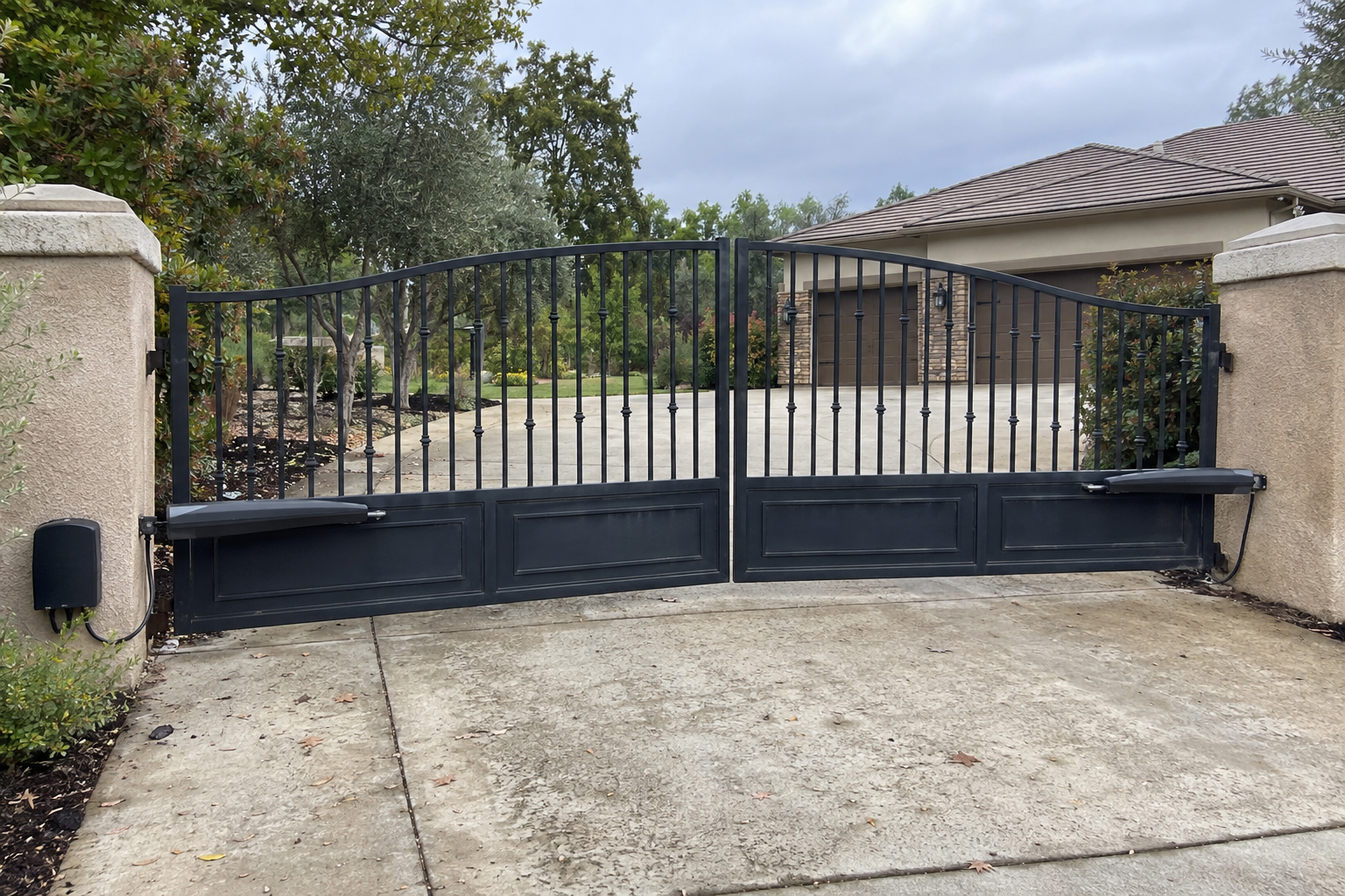 Wide dual-swing driveway gate with a linear operator arm on each leaf