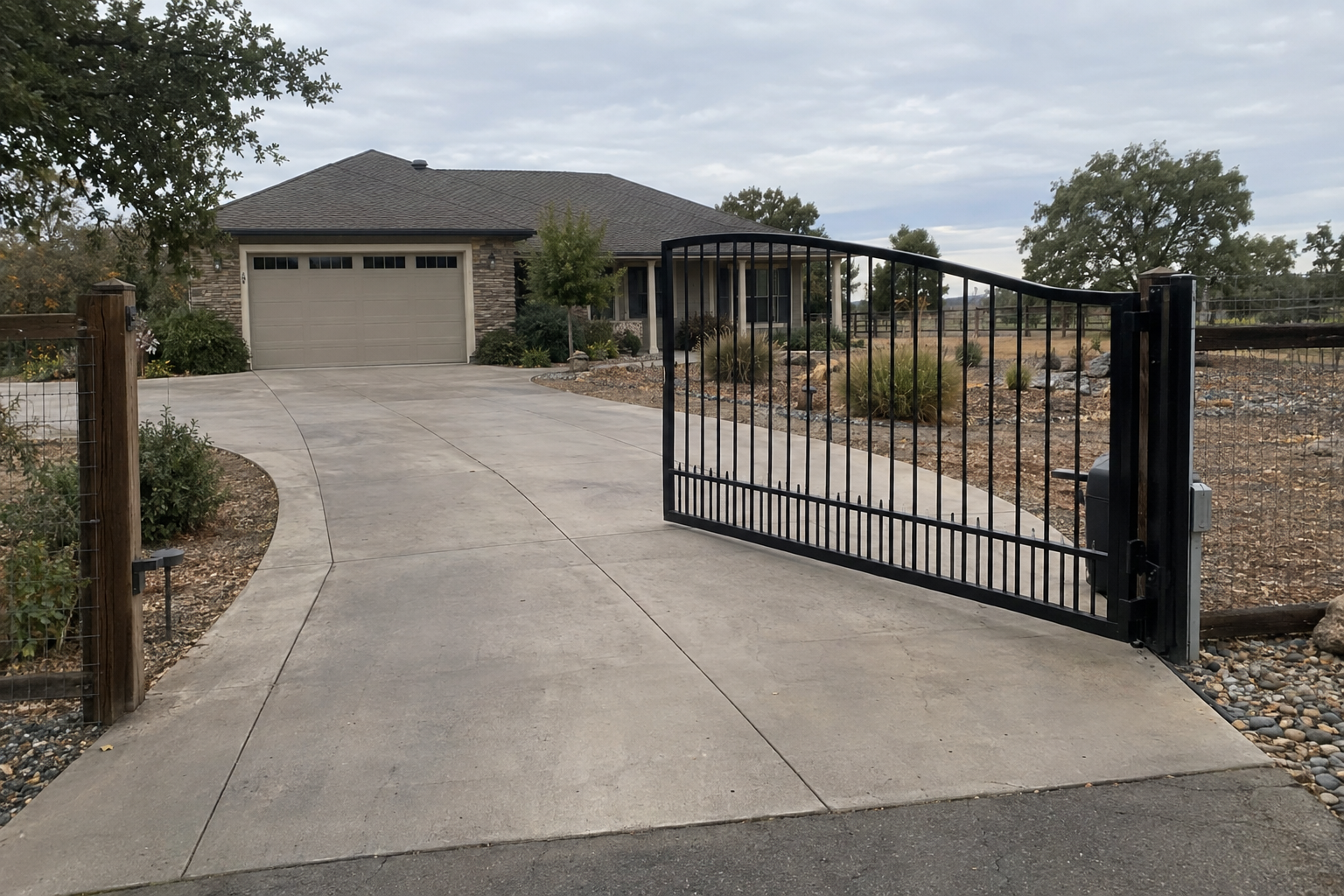A single-leaf black metal swing driveway gate open at an angle showing its arc