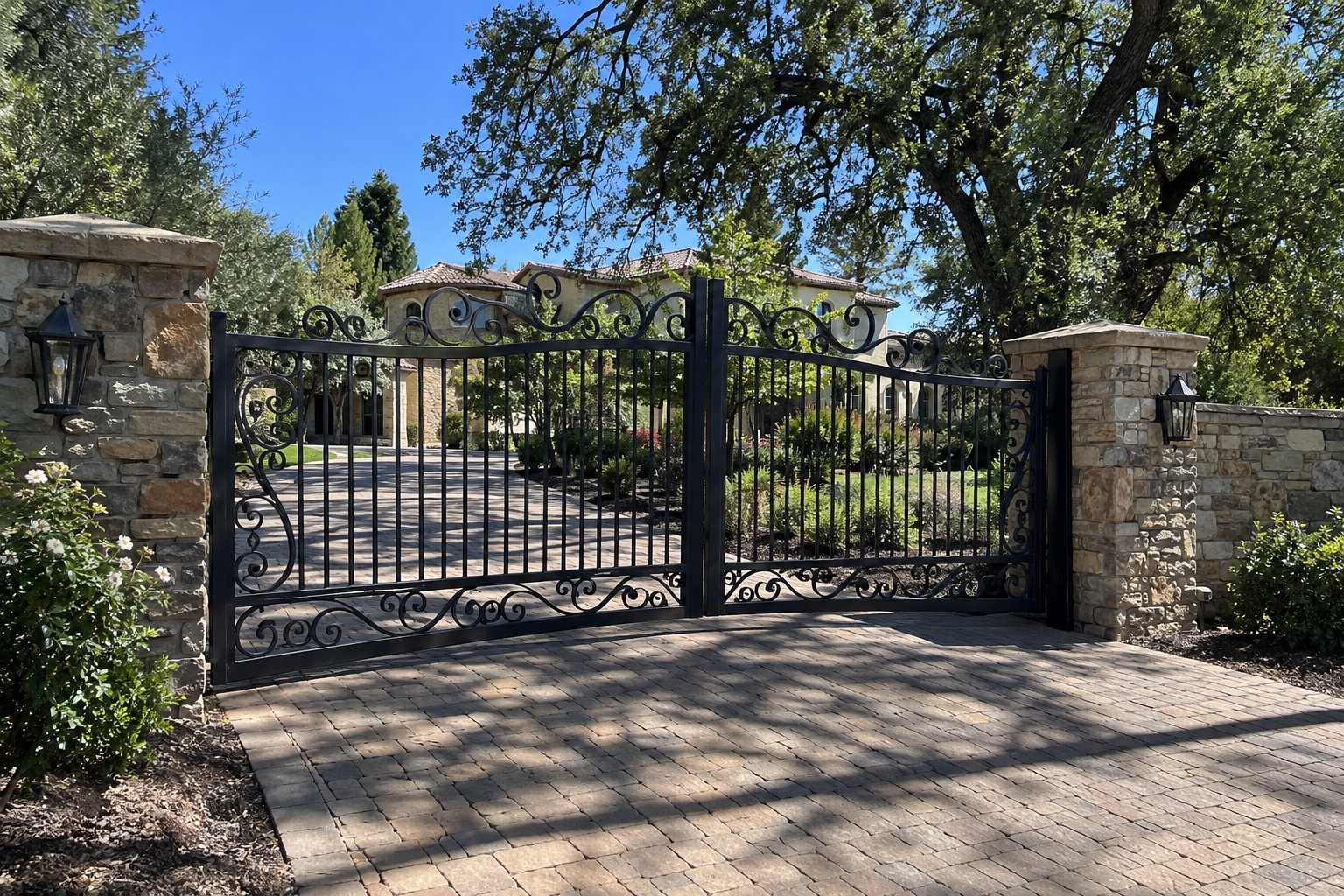 Ornamental wrought iron driveway gate with custom scrollwork between stone pillars on a Sacramento-area property