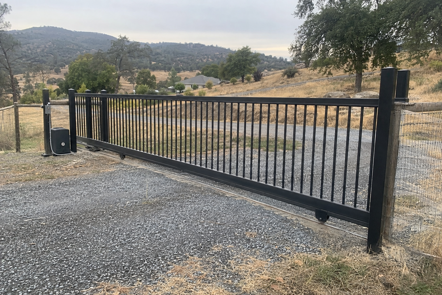 Long black metal sliding driveway gate on a track at a semi-rural Sacramento-area property
