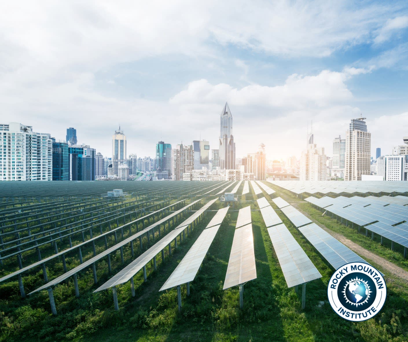 A field with solar panels with tall high rise buildings in the background