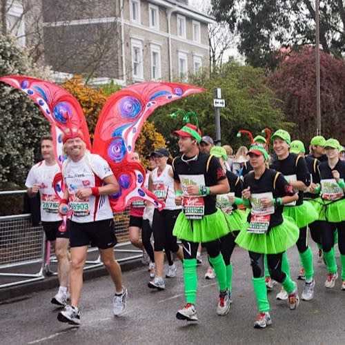 Richard Branson wearing butterfly wings leading a group of people dressed as a caterpillar on the London Marathon