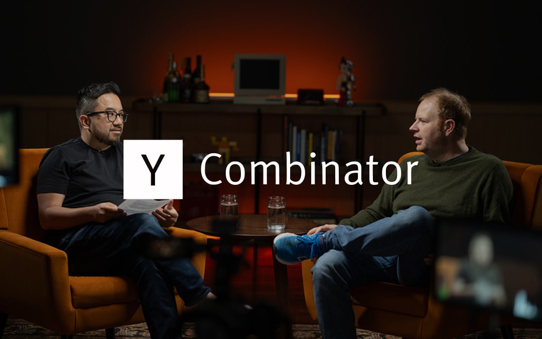 Y Combinator logo over a photograph of Y Combinator President and CEO Garry Tan talking to Rippling CEO Parker Conrad