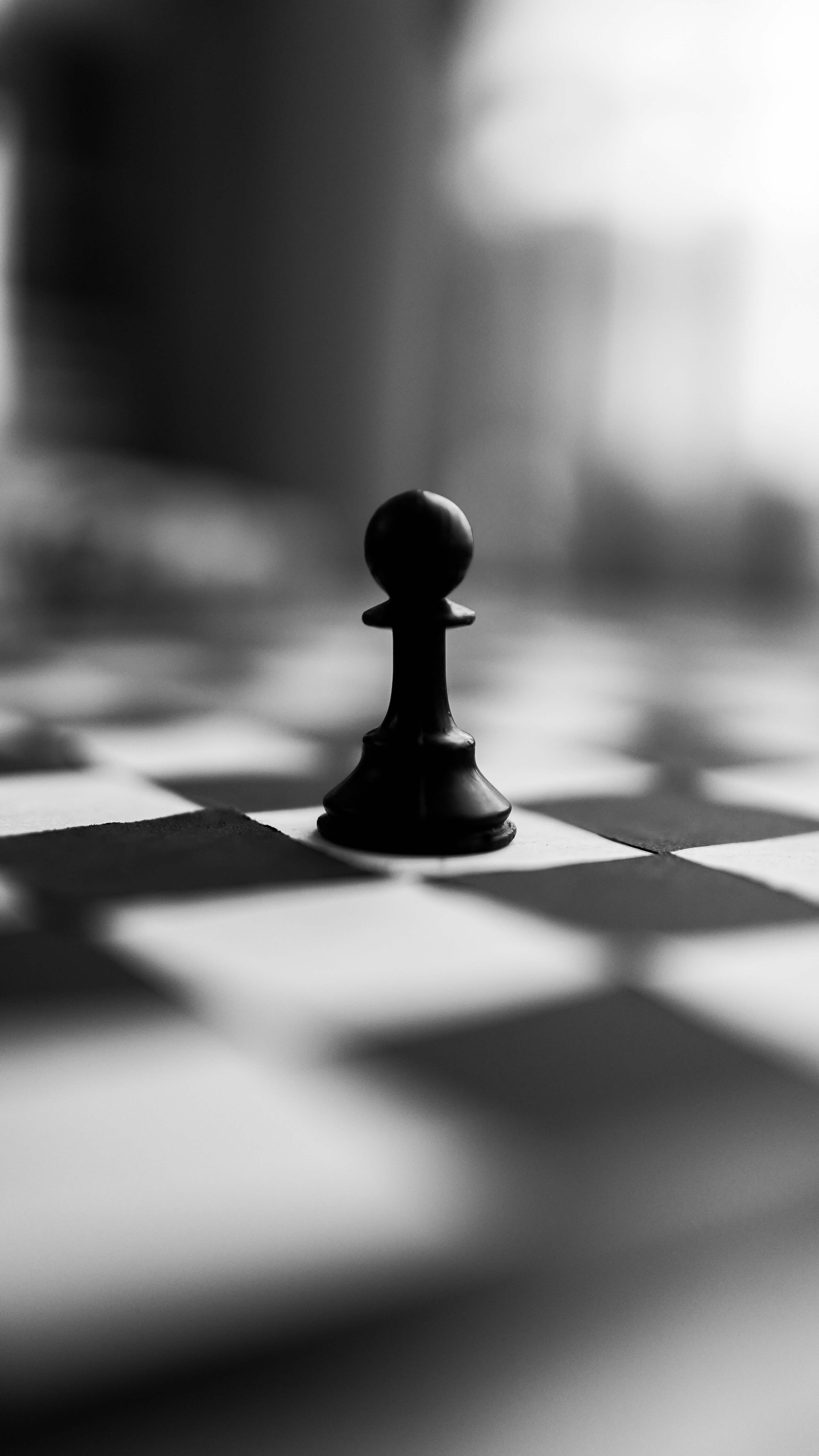 A pawn chess piece sitting on a chess board. 