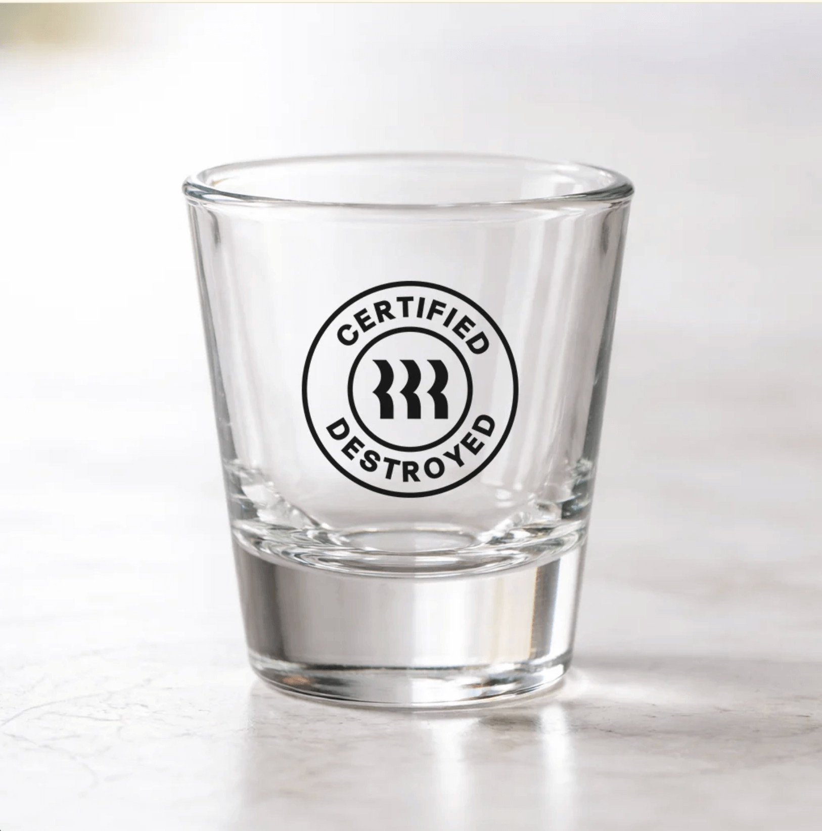 A shot glass with a branded stamp logo for Rippling IT reading "Certified Destroyed."