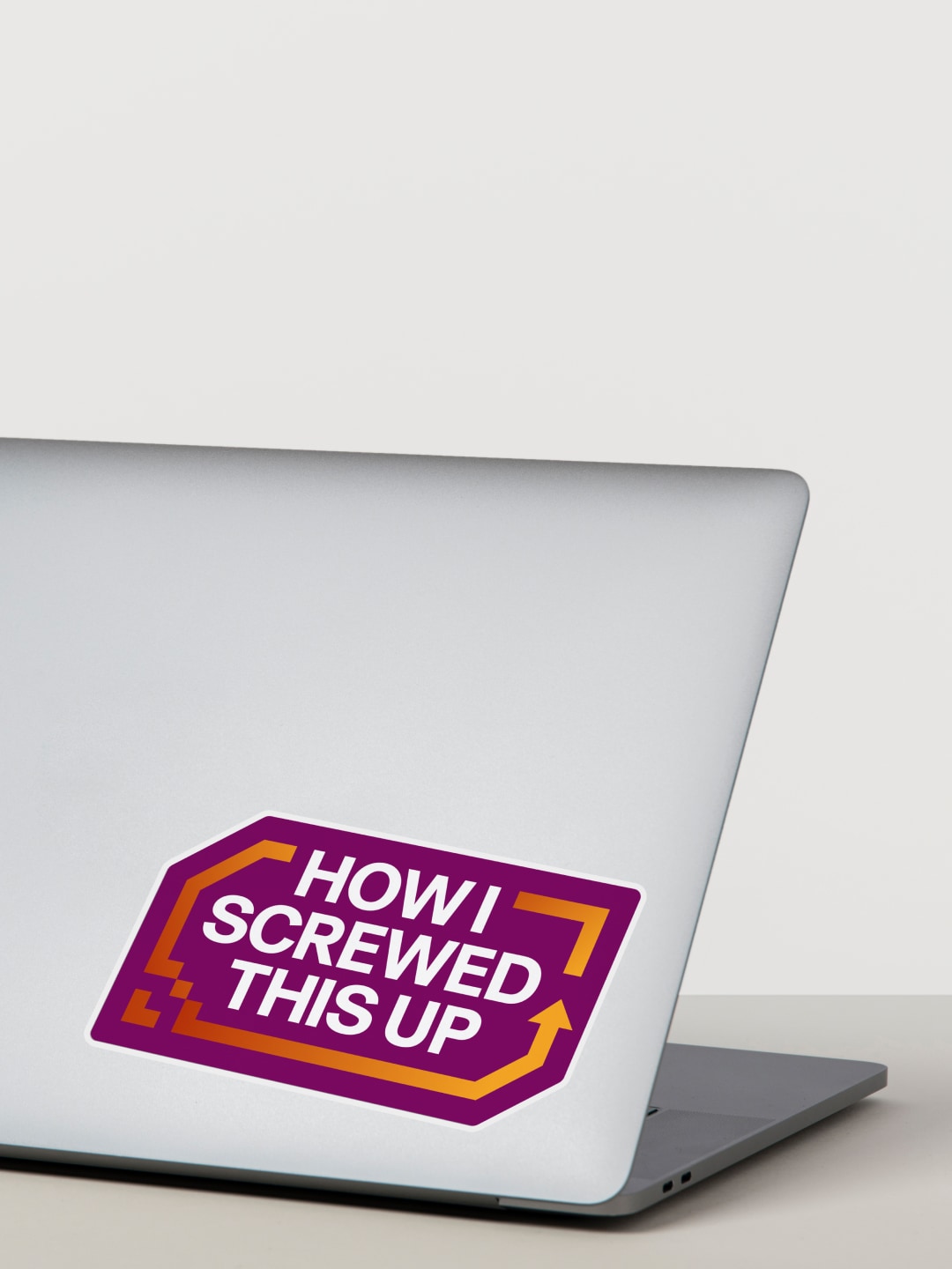 Photograph of a laptop with a sticker on the cover that says How I Screwed This Up