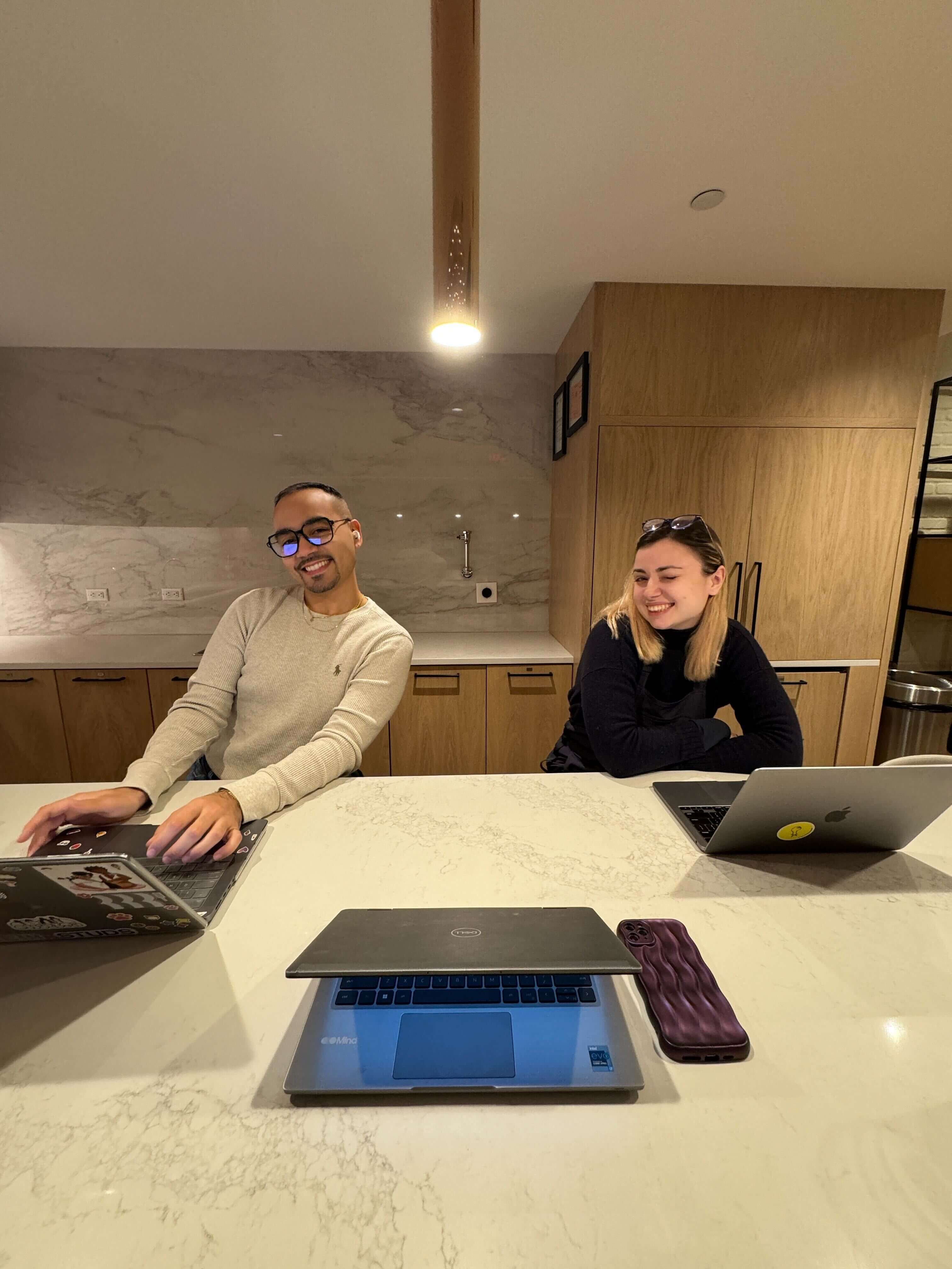 Geo and another person sitting in a meeting room with laptops. 