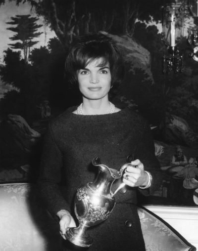 First Lady Jacqueline Kennedy holds a silver pitcher presented as a gift for the White House by James Hoban Alexander. Diplomatic Reception Room, White House, Washington, DC. Photo courtesy of John F. Kennedy Presidential Library and Museum.