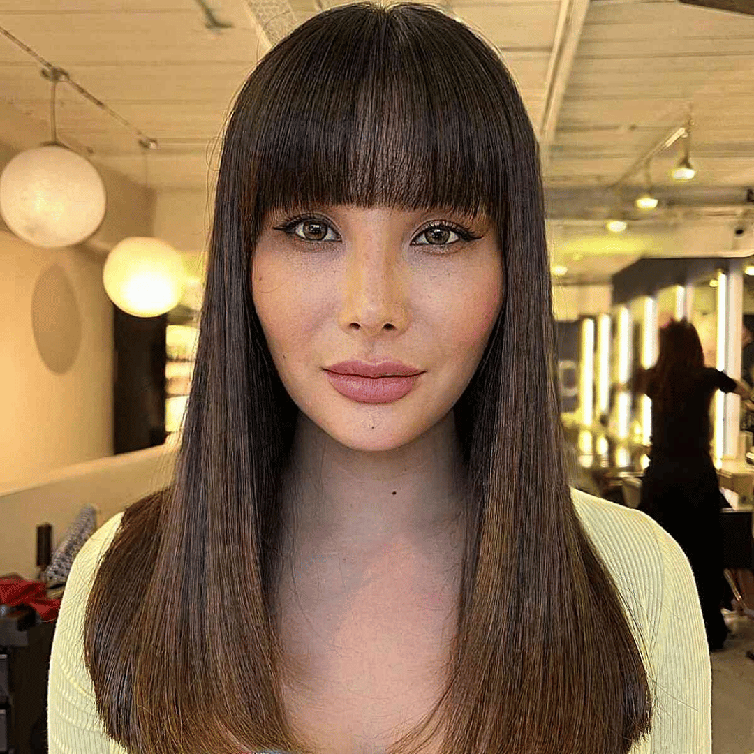 Woman with blunt bangs framing her heart-shaped face. 