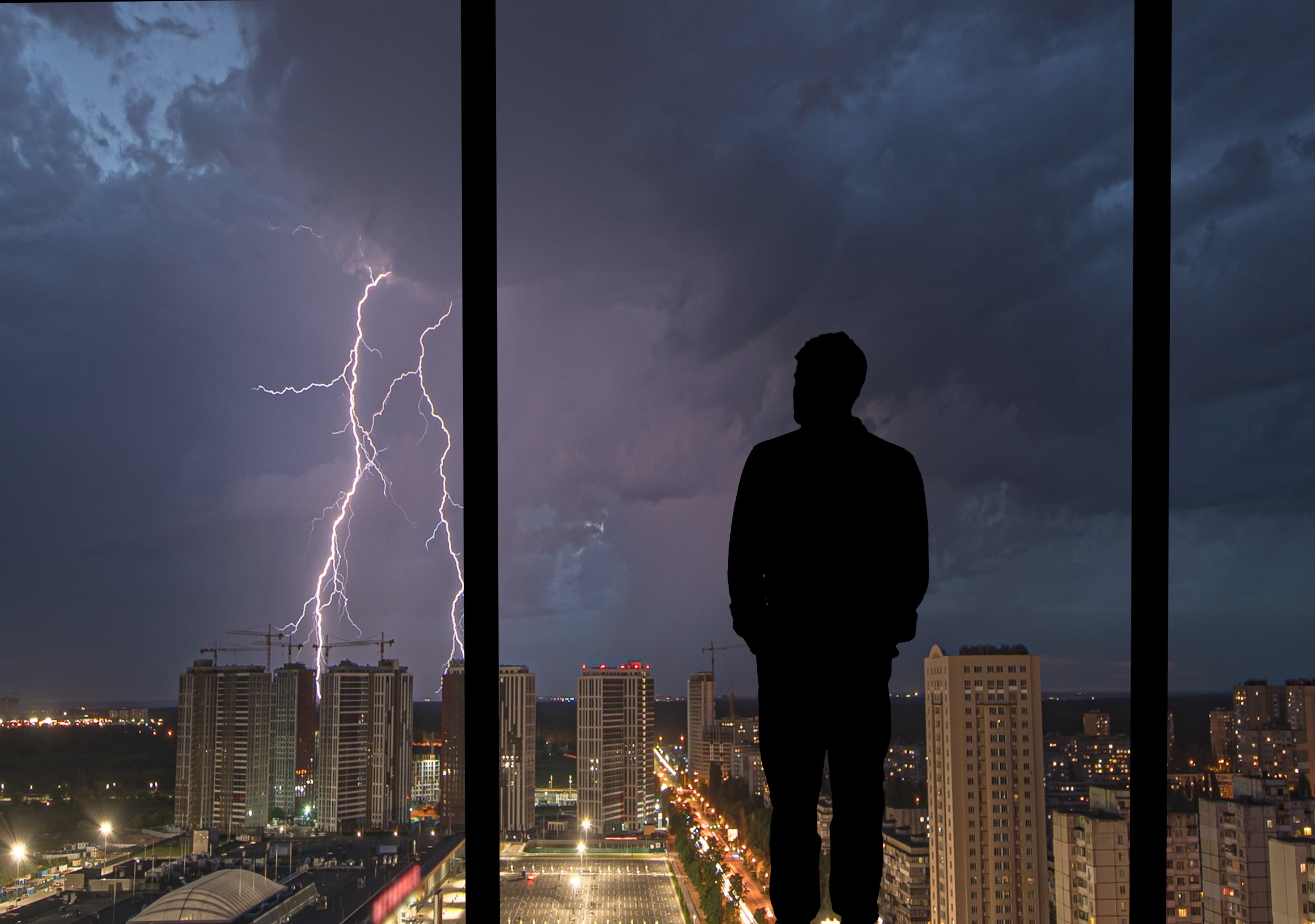 The truth about training OpenAI on your data - man standing looking out of window at cityscape during a lightening storm