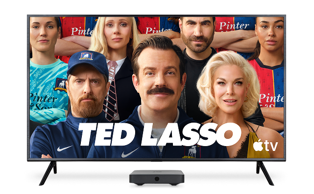 A TV displaying the poster for ‘Ted Lasso’ with the Apple TV logo on the bottom right.