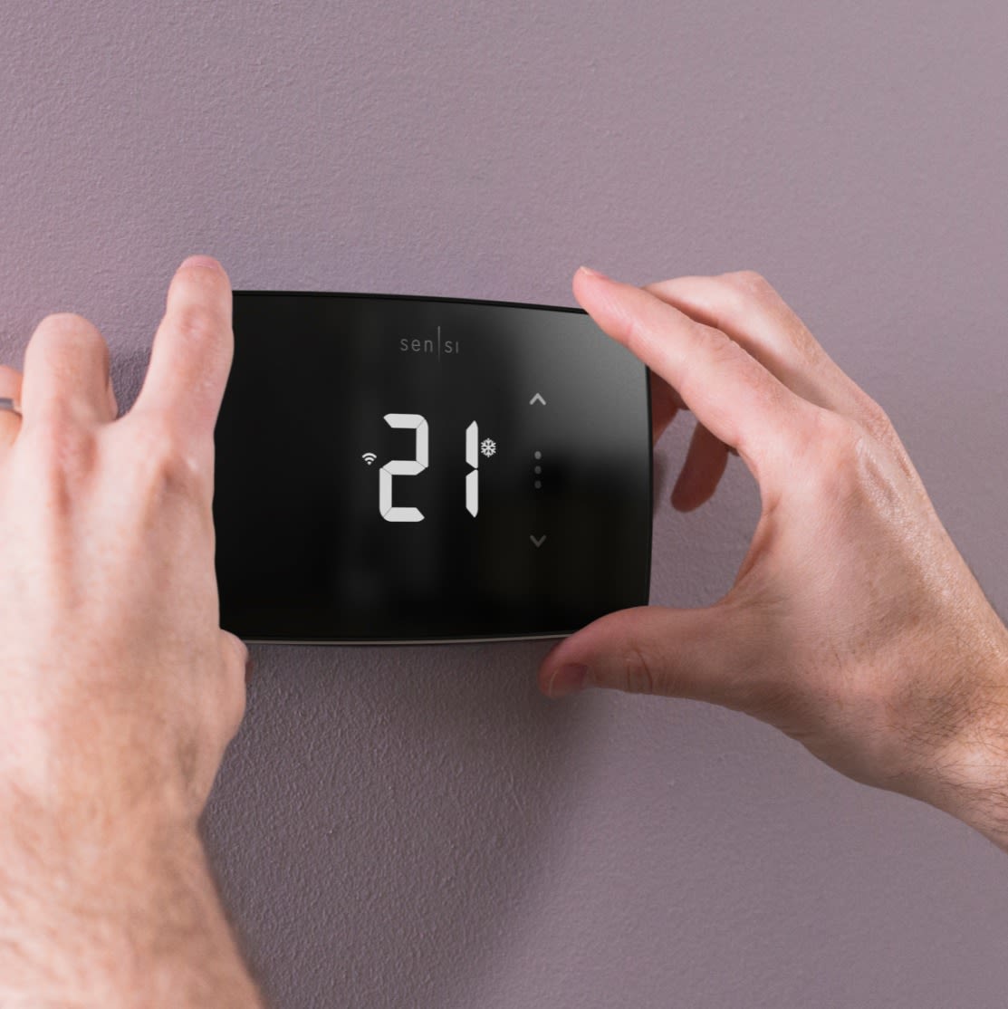 A person adjusting the temperature on a Sensi Lite Smart Thermostat.