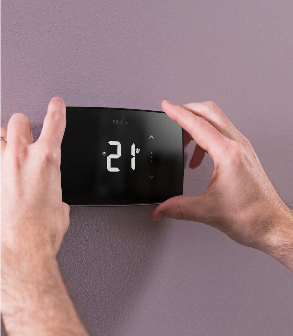 A person adjusting the temperature on a Sensi Lite Smart Thermostat.
