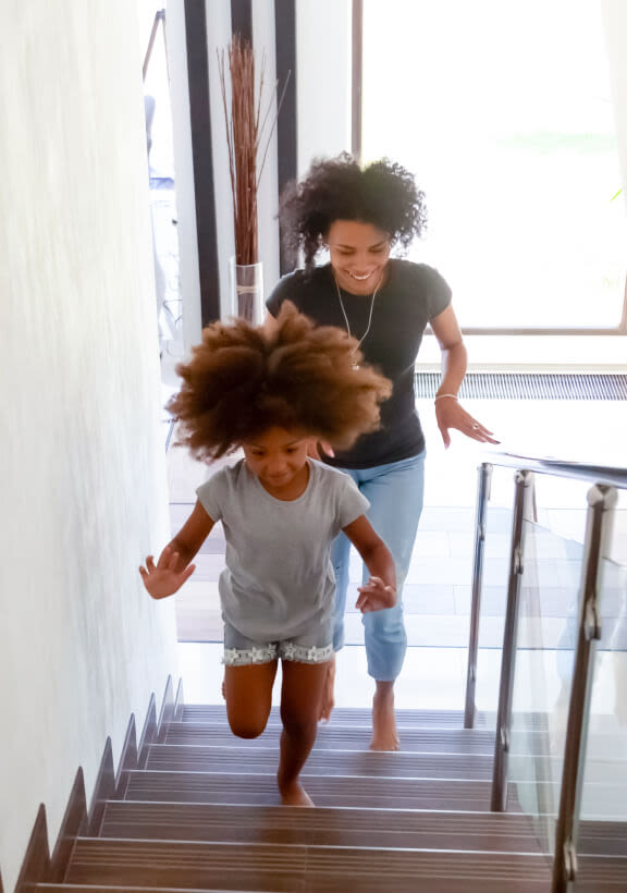 A TELUS Indoor Camera captures a family running up the stairs in the house.
