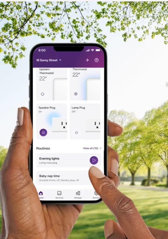 Hand holding smartphone with Kasa app interface for controlling smart lighting, outdoors with greenery background.