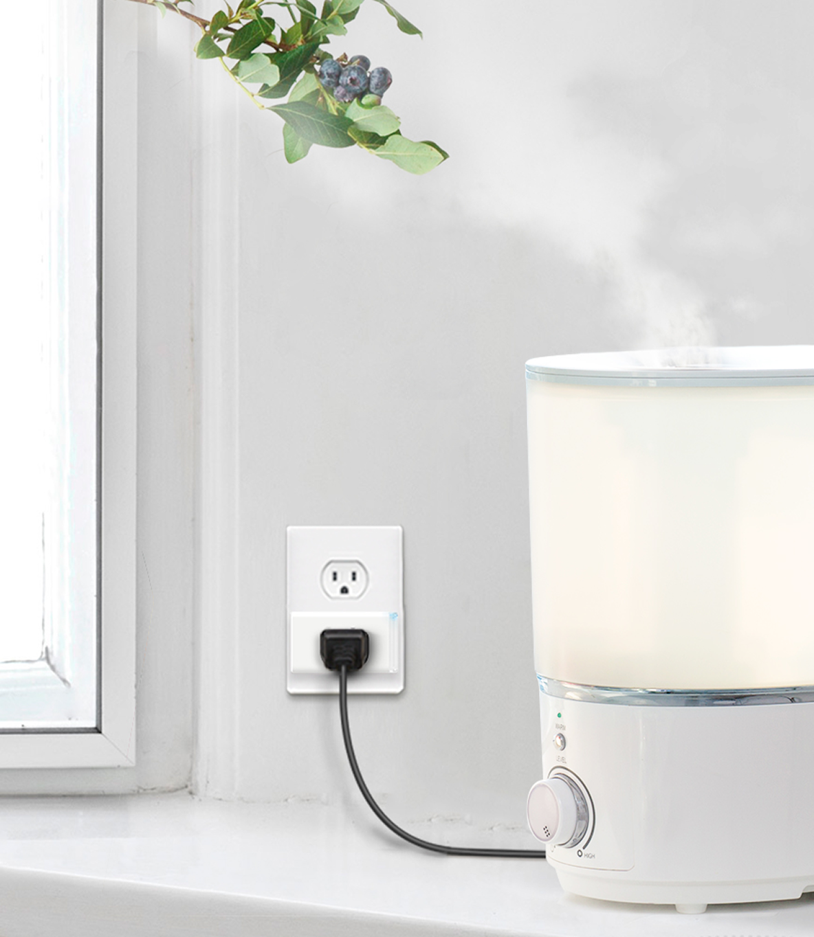 Lifestyle shot of a Kasa Smart Plug Mini plugged into a wall, with a humidifier plugged into it.