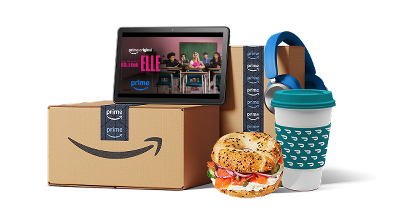 Amazon Prime boxes with a tablet playing a Prime Original, a bagel, a coffee cup, and blue headphones.