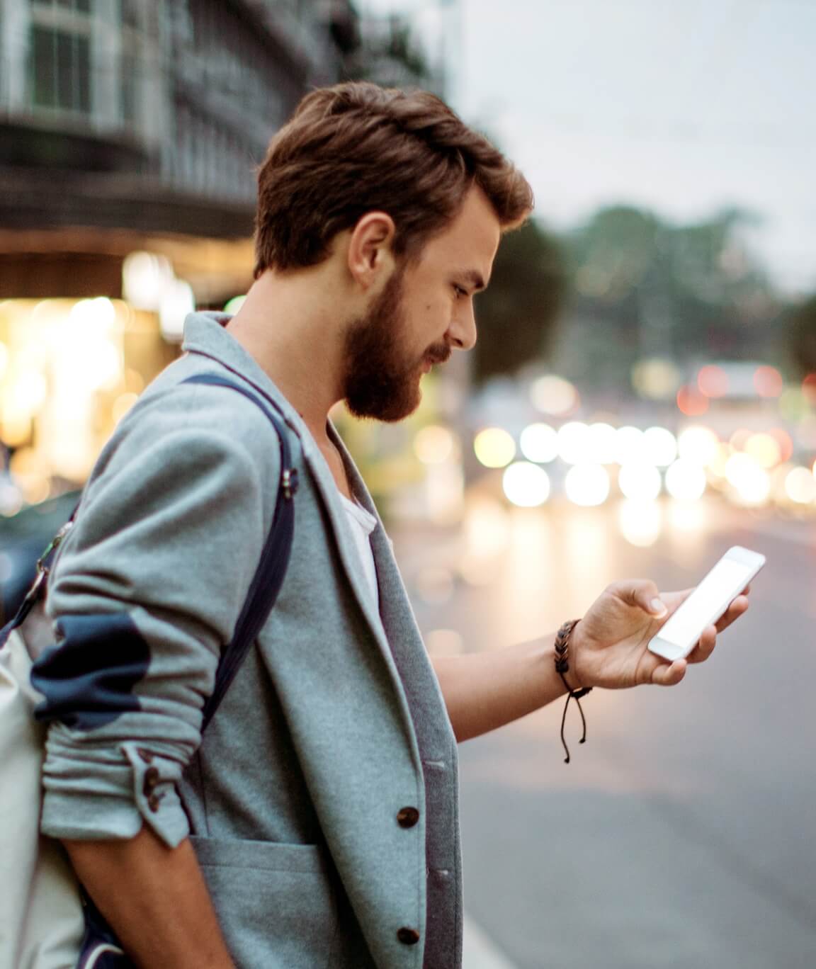 Man using smartphone to control smart lighting while walking outdoors with blurred city background.