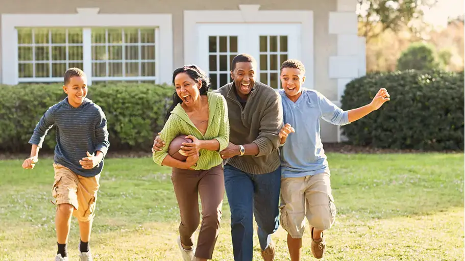 A family outside playing football together in the grass
