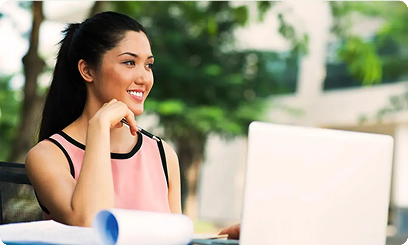 A woman sitting outside working on a laptop, representing the lifestyle of living with allergies.