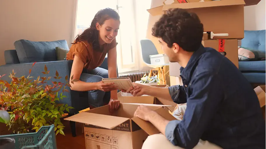 Two people unpacking boxes in a living room, highlighting the importance of understanding dust allergy symptoms and the potential impact of dust mites allergy in indoor environments.