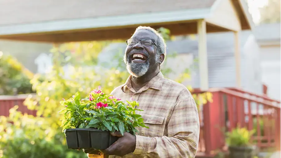 A person outside smiling holding flowers to plant