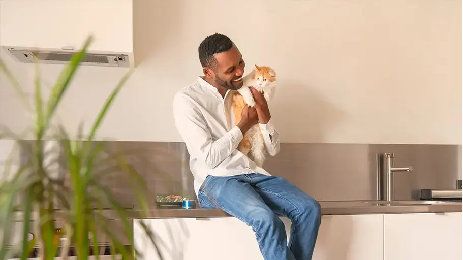 Person sitting in a kitchen holding a cat