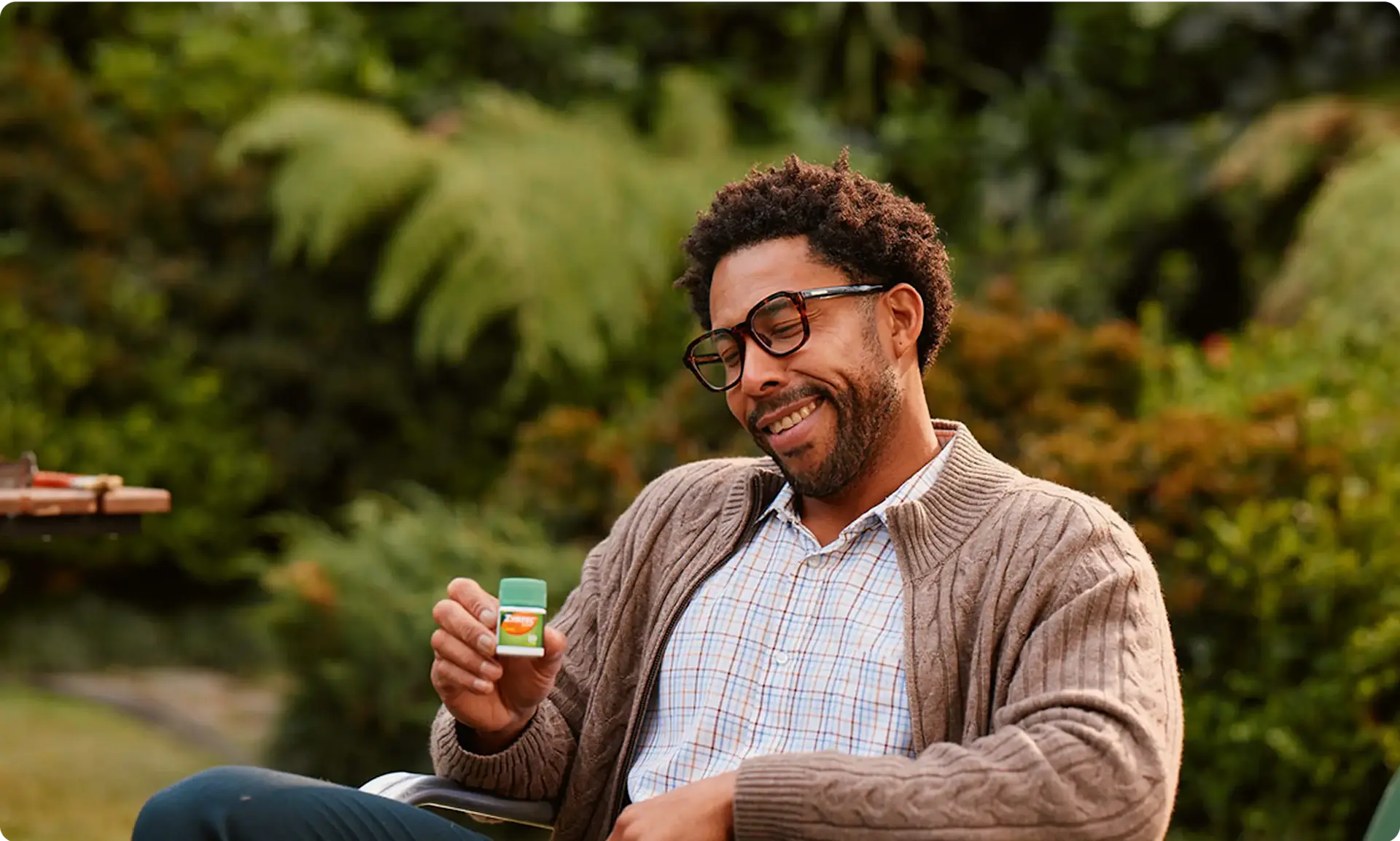 A person sitting in a chair outside holding ZYRTEC® Allergy Relief Medicine Tablets