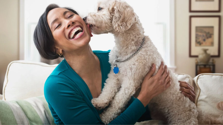 Woman smiling with her dor licking her cheek.