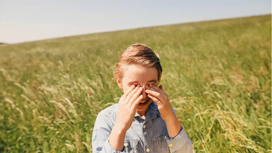 A person in a field touching their face
