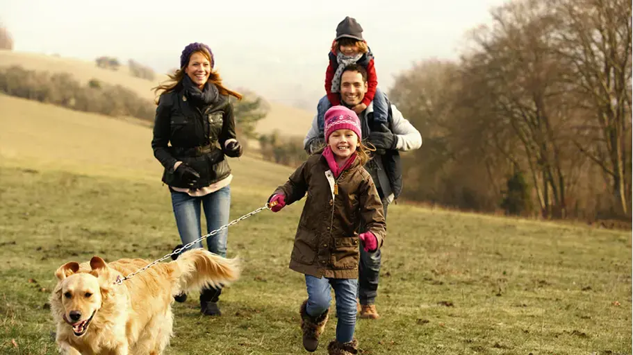 A family bundled up outside with their dog in a field during the winter