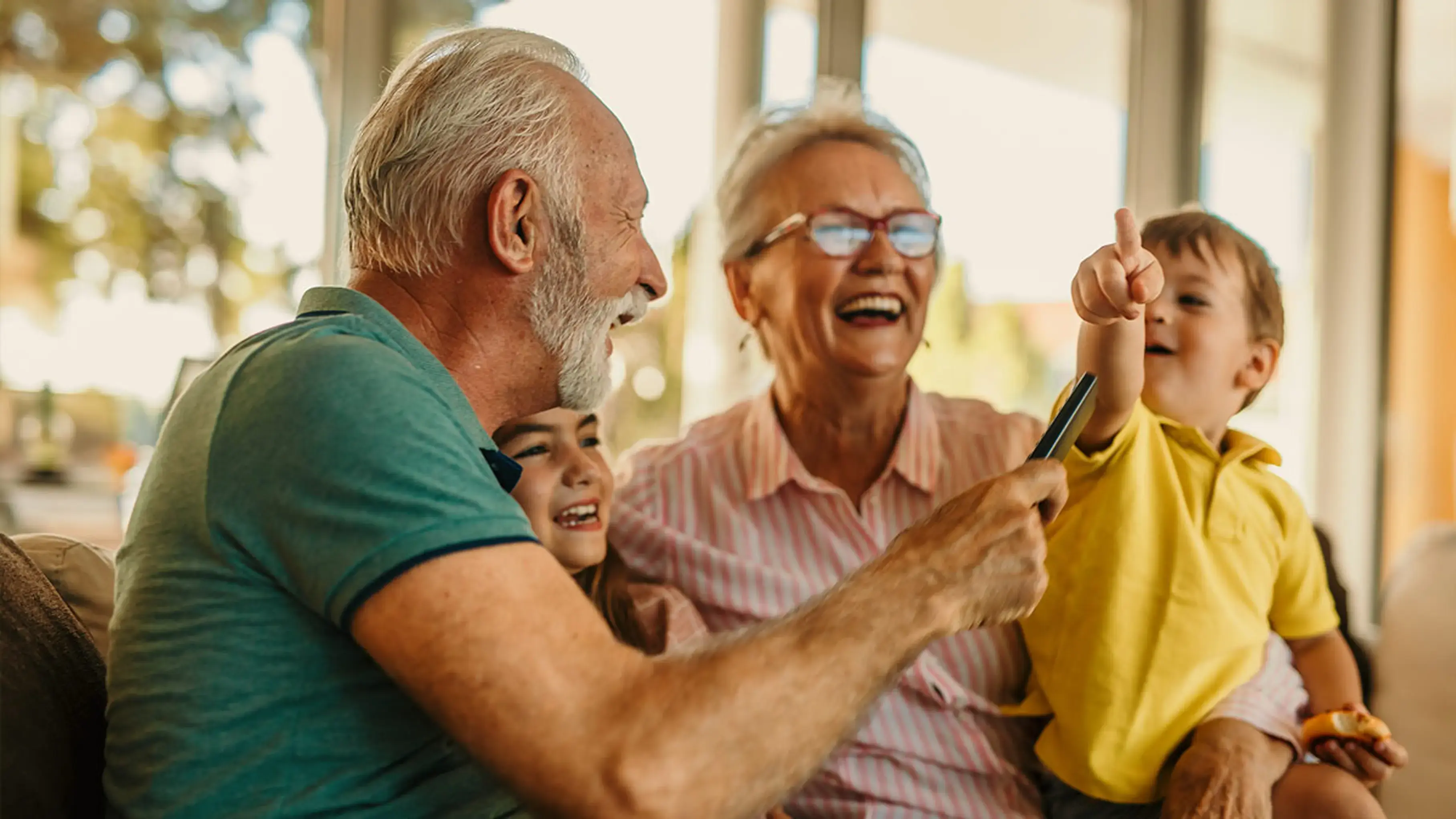 Older couple and two children smiling together, with one child pointing at the sky.
