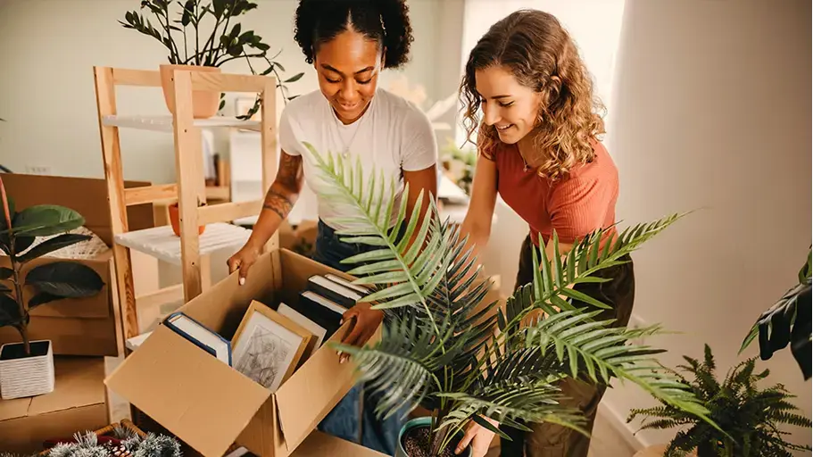 Two people unpacking surrounded by plants & boxes