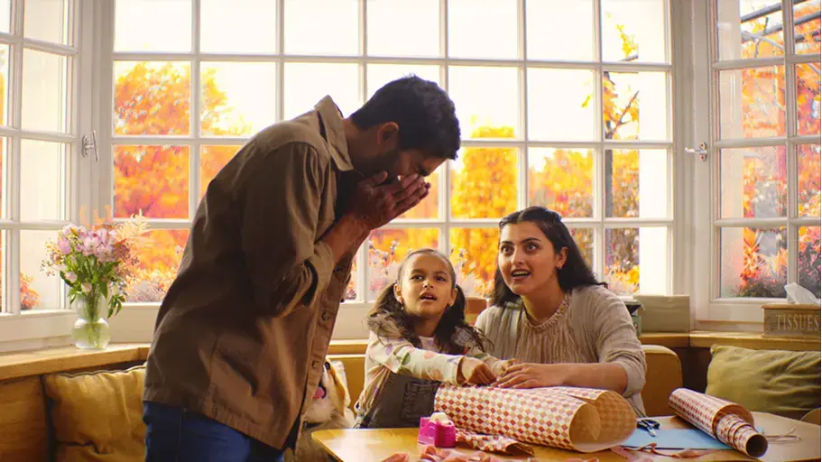 A person sneezing with their family wrapping gifts in the background