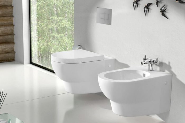 Clean, minimalist, modern bathroom with a wall-attached toilet and bidet