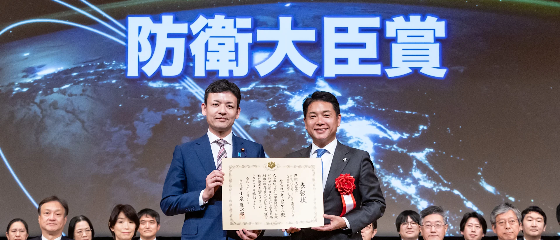 Nobu Okada, CEO and Founder of Astroscale, receiving the Minister of Defense award certificate at a Japanese defense ceremony with officials seated in the background.