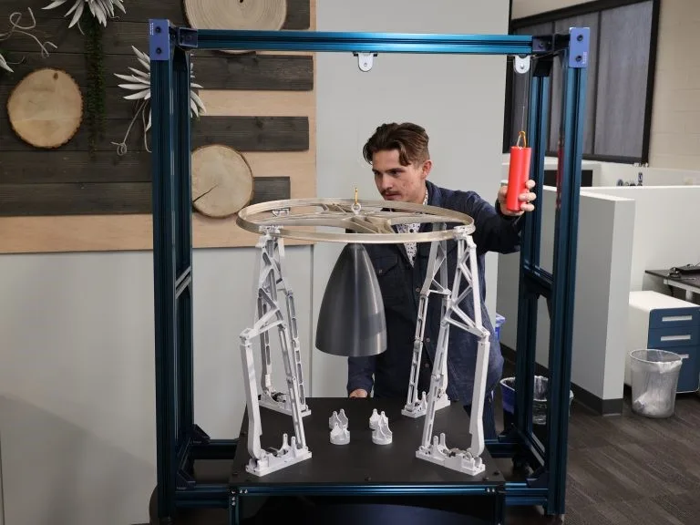 An Astroscale U.S. intern demonstrates his docking arms model