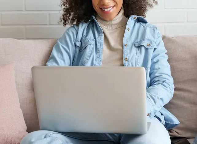 Woman sitting on a couch and looking at a laptop