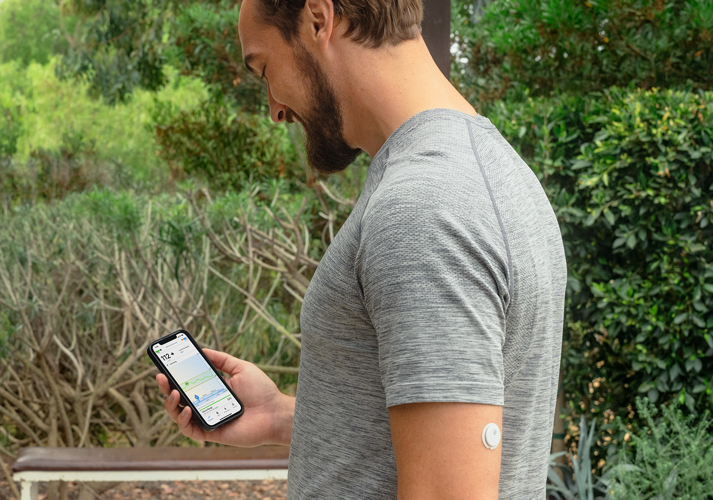 t:slim X2 Pump User Looking at their Mobile App with a FreeStyle Libre 3 Plus Sensor on their Arm