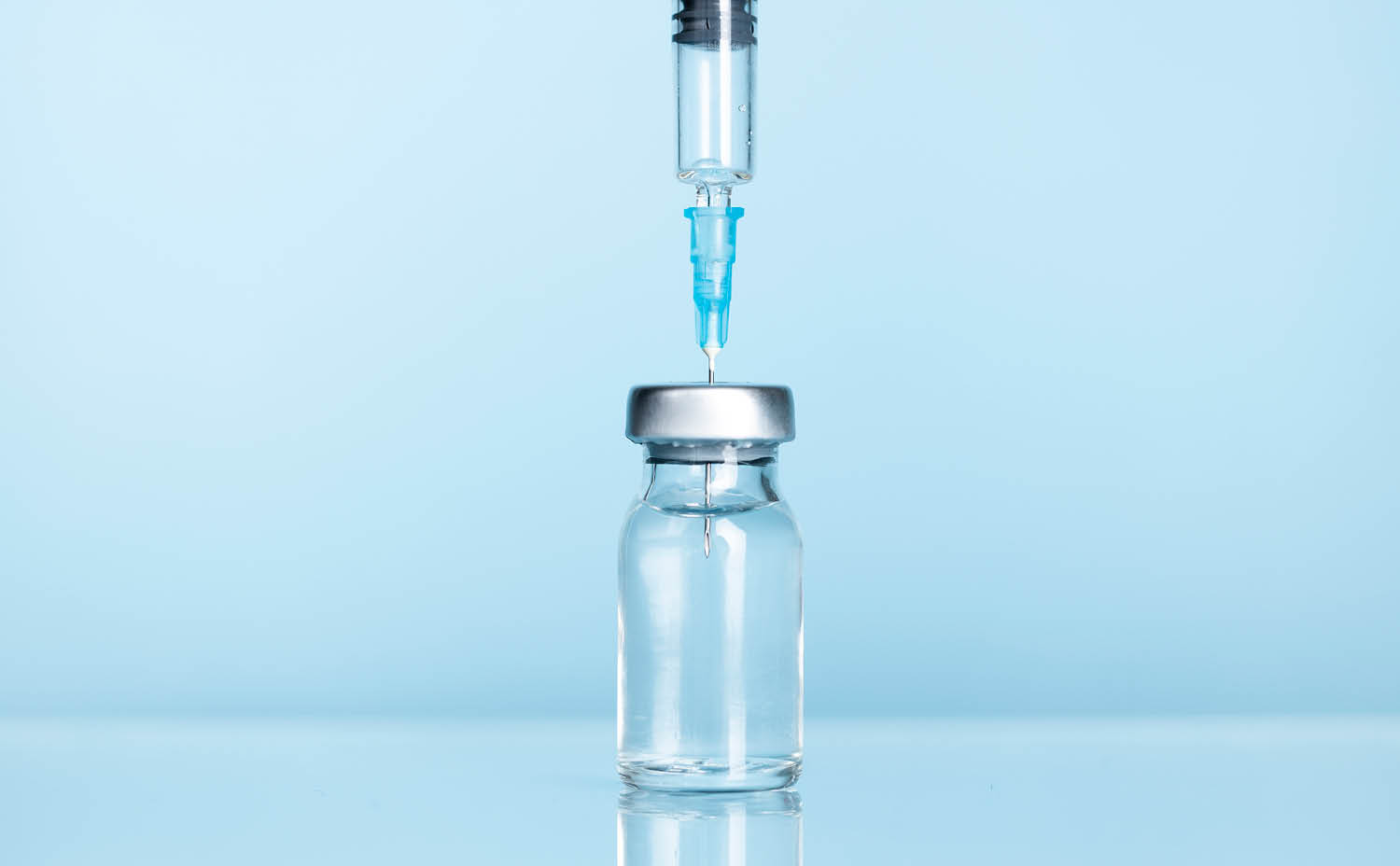 A syringe is inserted into a vial