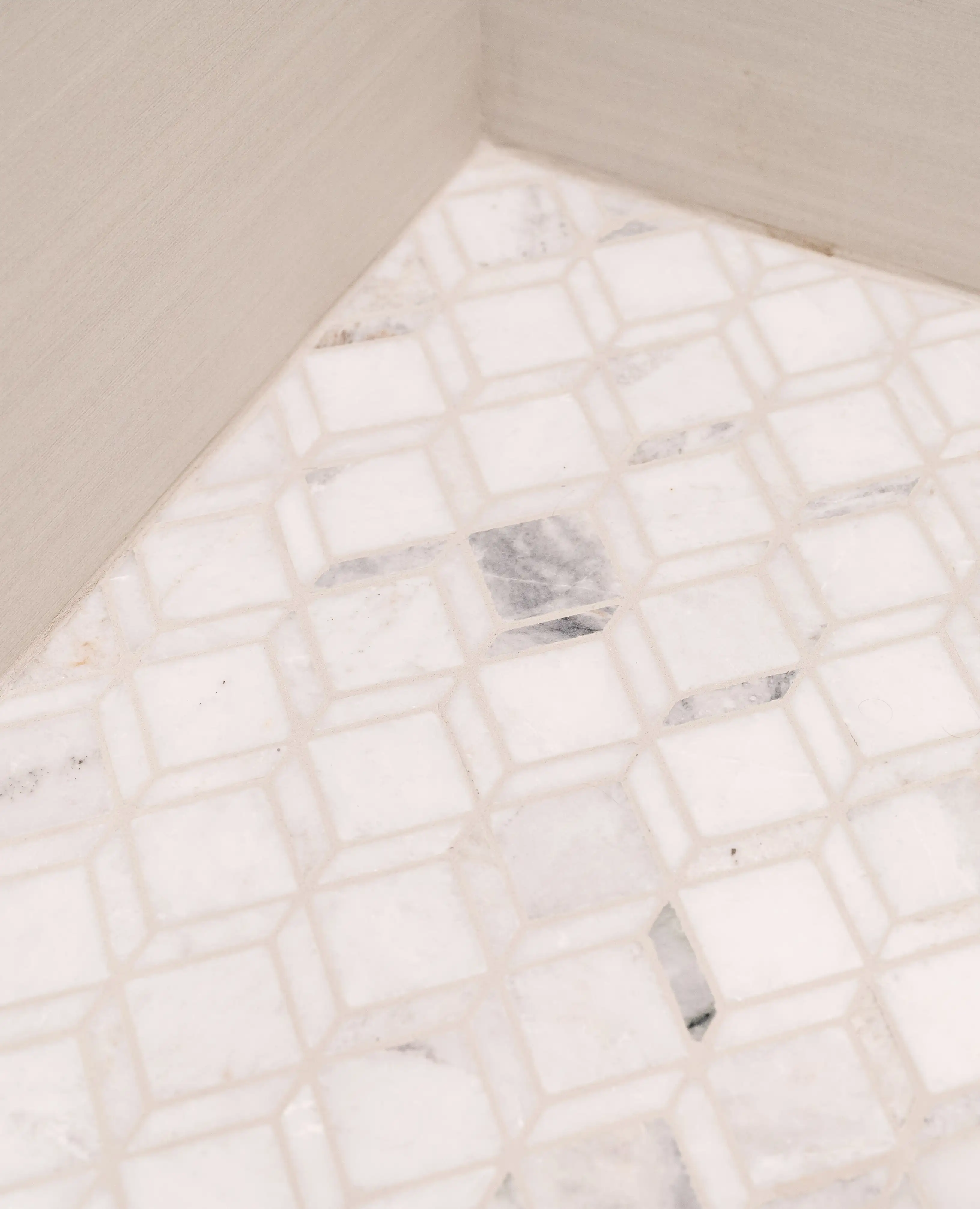 A shower with mosaic marble tile floor and wood like tile walls. 